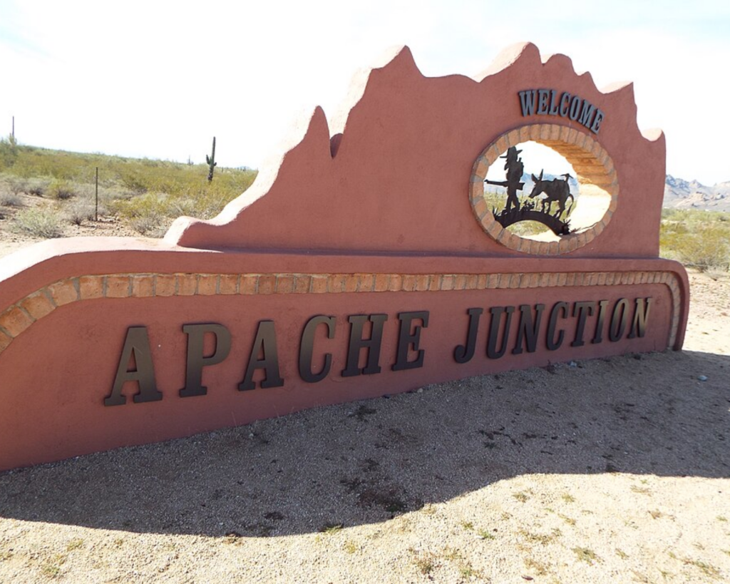 Welcome sign for Apache Junction, Arizona, featuring desert-themed artwork, mountain-shaped design, and large “Apache Junction” lettering.