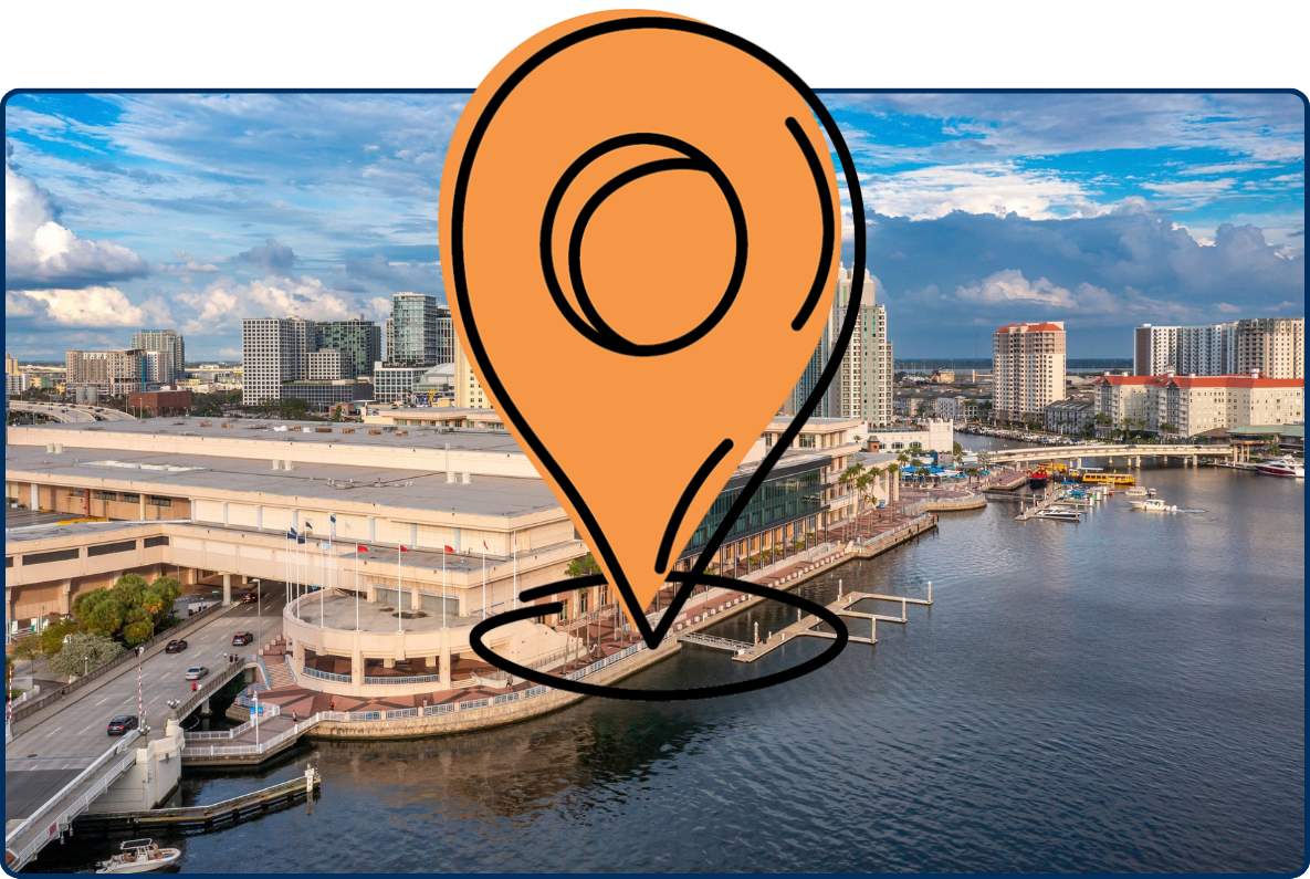 Aerial view of Tampa’s Channelside waterfront and Convention Center in Florida, with high-rise buildings, bridges, marina waters, and a partly cloudy sky.
