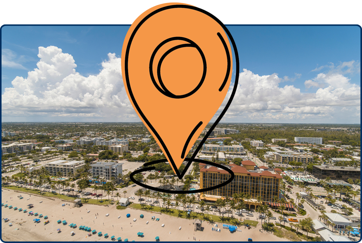 Aerial view of Deerfield Beach, Florida, showing a sandy beach, palm-lined hotels, surrounding neighborhoods, and dramatic white clouds under a bright blue sky.
