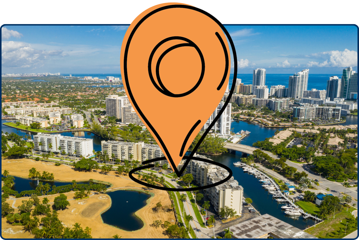 Aerial view of Hallandale Beach, Florida, showing high-rise buildings, waterways, roads, green spaces, and the Atlantic Ocean in the distance.