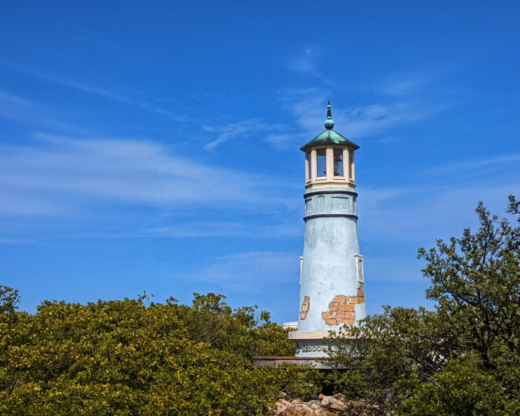 Harbour Island Lighthouse in Tampa, Florida, featuring a tall pale-blue tower with a lantern room and green roof against a clear blue sky.