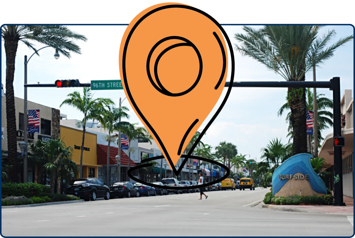 Street entrance to Surfside, Florida, at 96th Street, lined with palm trees, shops, parked cars, traffic lights, and a large Surfside welcome sign.