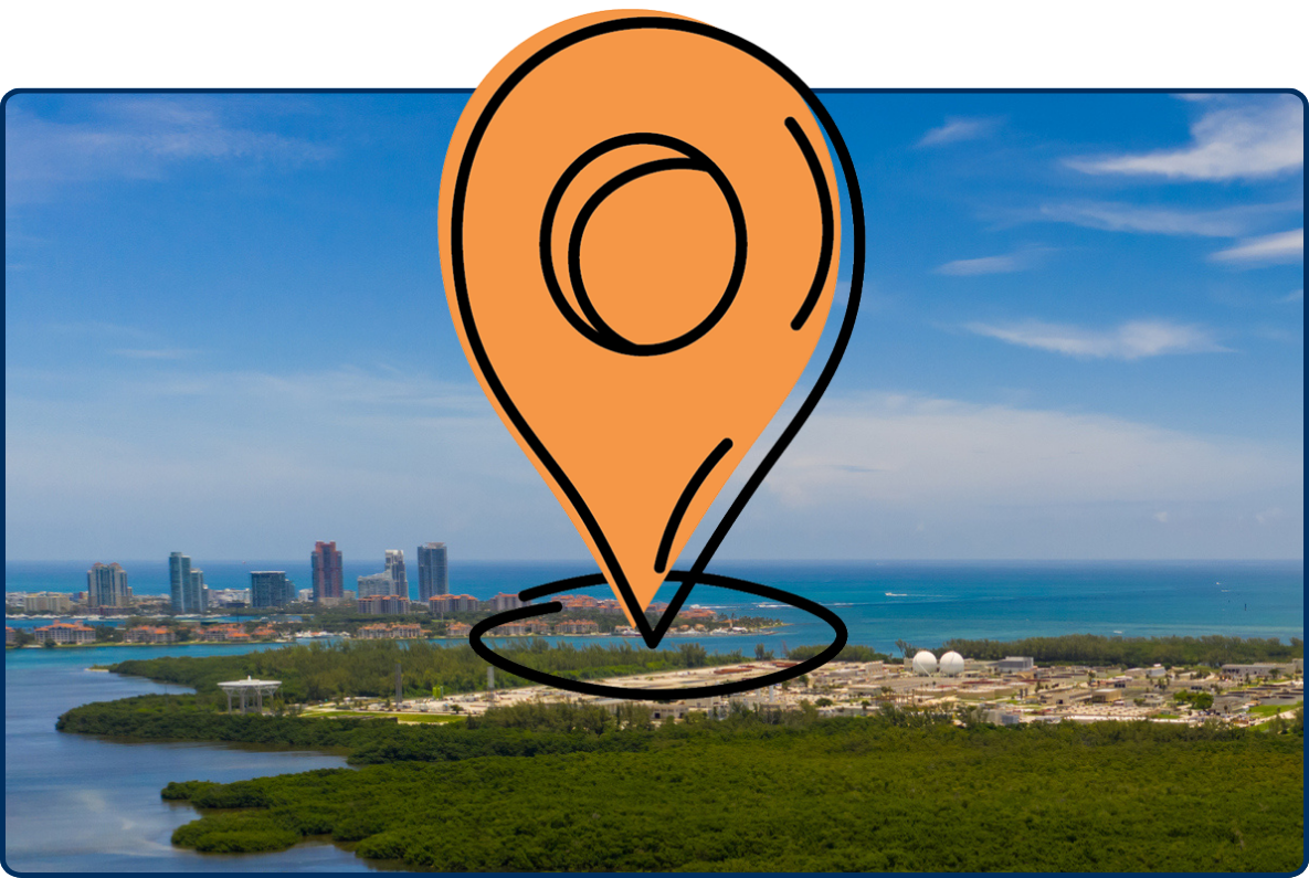 Aerial view of Virginia Key in Miami, Florida, showing dense green mangroves, surrounding waterways, the Atlantic Ocean, and distant high-rise buildings beneath a bright blue sky.
