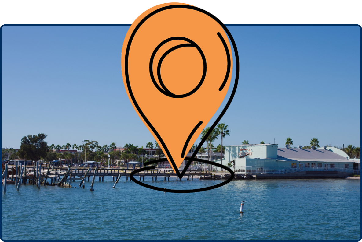 Coastal waterfront scene in Gulfport, Florida, with calm blue water, wooden docks, low-rise shoreline buildings, palm trees, and a clear blue sky.