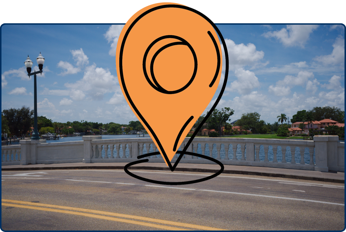 View from Snell Isle Bridge in St. Petersburg, Florida, overlooking calm bay waters, waterfront homes, palm trees, a white balustrade, and a blue sky with scattered clouds.