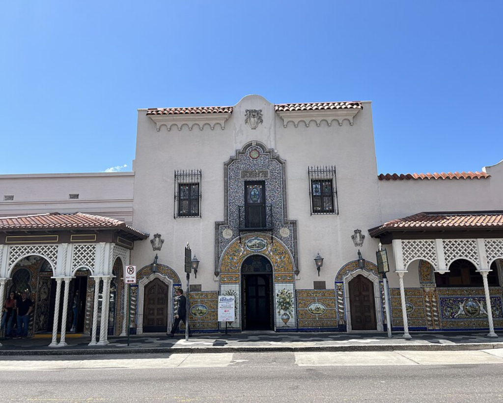 Columbia Restaurant in Ybor City, Tampa, Florida, featuring an ornate historic facade with decorative tilework, arched entrances, red-tiled roofs, and a bright blue sky.