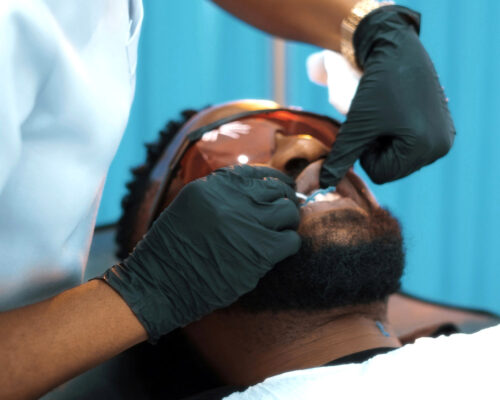 Dentist performing professional dental treatment on patient in chair with protective gloves